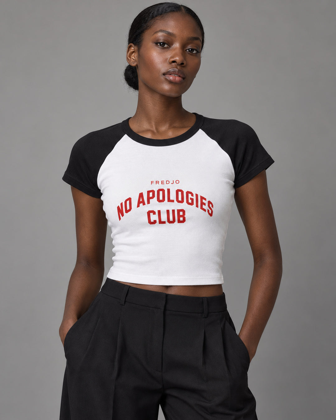 No Apologies Club baby tee in white and black, worn by a woman