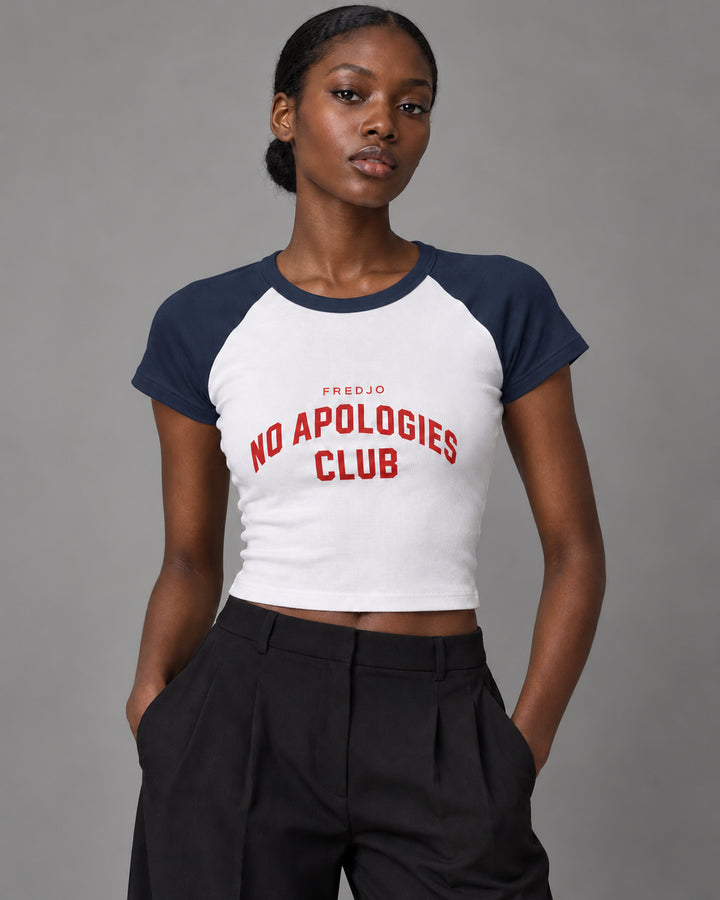 No Apologies Club baby tee in white and navy, worn by a woman